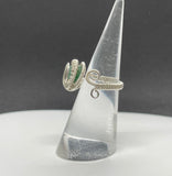 This stunning adjustable ring features a mesmerizing Green Goldstone, wire wrapped in Argentium Silver. The rich green tones of the Goldstone sparkle with flecks of silver, creating a captivating effect that catches the light beautifully. The ring's adjustable design ensures a perfect fit for various finger sizes, making it a versatile and elegant addition to any jewelry collection. The combination of the shimmering Green Goldstone and the sleek Argentium Silver creates an eye-catching piece.