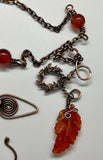 A carnelian leaf pendant rests on copper, accented with carnelian beads and delicate copper leaves — this necklace is a piece that feels alive, like autumn caught in motion.