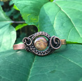 This Hand Woven Copper Cuff Bracelet with Cherry Creek Jasper is a striking piece of jewelry featuring a solid copper cuff with an intricately woven Cherry Creek Jasper centerpiece. This bracelet combines the warmth and durability of copper with the natural beauty of Cherry Creek Jasper, creating a unique and elegant accessory.