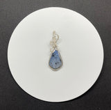 This Beautiful Blue Dumortierite Pendant features a striking blue dumortierite gemstone elegantly encased in wire-wrapped sterling silver. This pendant combines the rich, deep blue tones of dumortierite with the refined sparkle of sterling silver, creating a sophisticated and eye-catching piece of jewelry.