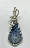 This Beautiful Blue Dumortierite Pendant features a striking blue dumortierite gemstone elegantly encased in wire-wrapped sterling silver. This pendant combines the rich, deep blue tones of dumortierite with the refined sparkle of sterling silver, creating a sophisticated and eye-catching piece of jewelry.