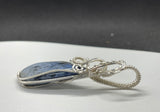 This Beautiful Blue Dumortierite Pendant features a striking blue dumortierite gemstone elegantly encased in wire-wrapped sterling silver. This pendant combines the rich, deep blue tones of dumortierite with the refined sparkle of sterling silver, creating a sophisticated and eye-catching piece of jewelry.
