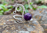 This Beautiful Purple Charoite and Hand Woven Sterling Silver Ring showcases a stunning charoite gemstone set in intricately hand-woven sterling silver. This ring combines the unique, vibrant hue of charoite with the elegance of sterling silver, creating a luxurious and eye-catching piece of jewelry.