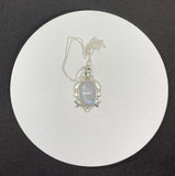 This enchanting pendant showcases a mesmerizing rainbow moonstone with an iridescent glow, set in a beautifully detailed sterling silver setting adorned with celestial stars and a crescent moon. Suspended on a 20" sterling silver chain, this piece captures the magic of the night sky, making it a perfect gift for dreamers and stargazers.