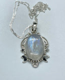 This enchanting pendant showcases a mesmerizing rainbow moonstone with an iridescent glow, set in a beautifully detailed sterling silver setting adorned with celestial stars and a crescent moon. Suspended on a 20" sterling silver chain, this piece captures the magic of the night sky, making it a perfect gift for dreamers and stargazers.
