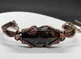 This Hand Woven Copper Bracelet with Candlelite and Purple Dumortierite Bead Accents is perfect for individuals who appreciate handcrafted, artisan jewelry with natural gemstones. It appeals to those who love earthy, rustic designs with a touch of elegance and vibrancy. The bracelet is ideal for those who seek unique, one-of-a-kind pieces that blend beauty and craftsmanship.