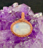 This pendant features a vibrant Rainbow Moonstone with a captivating play of colors. The stone is securely wrapped in intricate handwoven copper, enhancing its natural beauty while adding warmth and elegance.