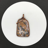 This Bold Flower Jasper Pendant in Copper features a striking and vibrant flower jasper stone set within a beautifully crafted copper frame. Known for its rich colors and intricate patterns, the flower jasper provides a dramatic focal point, while the copper setting enhances the pendant's natural beauty with a touch of artisanal elegance. This pendant is a statement piece that combines bold design with handcrafted quality.