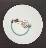 This vibrant turquoise-colored leather bracelet adds a pop of color to your accessory collection. Crafted with care, it features unique handmade hammered copper clasps that provide both durability and artistic flair. A charming flower dangle accentuates the design, adding a playful touch. This bracelet is not only stylish but also comfortable, making it a perfect choice for everyday wear or special occasions. Embrace the beauty of handcrafted jewelry with this delightful piece!