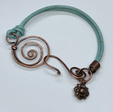 This vibrant turquoise-colored leather bracelet adds a pop of color to your accessory collection. Crafted with care, it features unique handmade hammered copper clasps that provide both durability and artistic flair. A charming flower dangle accentuates the design, adding a playful touch. This bracelet is not only stylish but also comfortable, making it a perfect choice for everyday wear or special occasions. Embrace the beauty of handcrafted jewelry with this delightful piece!