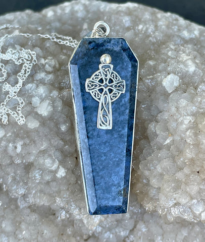 This captivating necklace features a deep blue Dumortierite stone, expertly shaped into a coffin design and set in sterling silver. The pendant is adorned with an intricate Celtic cross, symbolizing unity and eternal life. The contrast between the rich tones of the Dumortierite and the sleek sterling silver adds depth and elegance, making this piece perfect for those who appreciate symbolic, gothic-inspired jewelry with a touch of timeless craftsmanship.