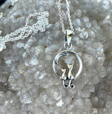 This delightful necklace features two miniature Sterling Silver cats under a crescent moon, evoking a sense of whimsy and wonder. Perfectly detailed, the pendant is both playful and elegant, making it an ideal gift for cat lovers and dreamers alike. Suspended on a 20" Sterling Silver chain, this necklace adds a touch of charm to any outfit.