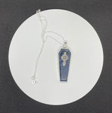 This captivating necklace features a deep blue Dumortierite stone, expertly shaped into a coffin design and set in sterling silver. The pendant is adorned with an intricate Celtic cross, symbolizing unity and eternal life. The contrast between the rich tones of the Dumortierite and the sleek sterling silver adds depth and elegance, making this piece perfect for those who appreciate symbolic, gothic-inspired jewelry with a touch of timeless craftsmanship.