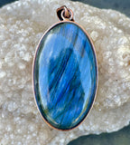 This bold pendant showcases a striking blue labradorite with vibrant flashes of color that dance in the light. Set in copper, the design enhances the stone’s natural iridescence and mystical appeal. A powerful statement piece, perfect for those drawn to the magic of labradorite.
