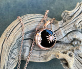 Bold and symbolic, this Copper and Obsidian Moon and Sun Necklace celebrates the balance of light and shadow. The design beautifully unites the radiant energy of the sun with the mysterious allure of the moon, creating a meaningful celestial statement piece.

Deep, glossy obsidian adds dramatic contrast to the warm glow of the copper. Its smooth, dark surface enhances the intricate metalwork while symbolizing protection and grounding energy.