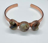 This celestial-inspired copper bangle features two Laguna Lace Agate crescent moons and one striking full moon centerpiece. The natural swirls and vibrant banding of the agate stones create a beautiful contrast against the copper setting. A symbolic and one-of-a-kind bracelet that captures the magic of moon phases.