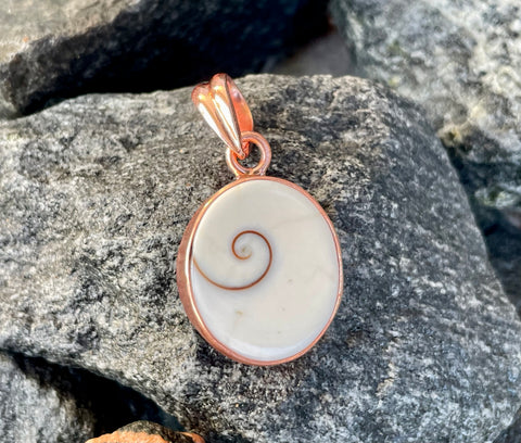 This unique pendant features a natural Shiva Shell, known for its mesmerizing spiral pattern and soothing energy. Set in warm copper, the design highlights the shell’s creamy tones and organic beauty.Sometimes call Shiva Eye Shell.