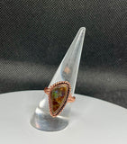Vibrant and captivating, this Ammolite Ring set in Copper showcases the stunning natural iridescence of ammolite. Flashes of brilliant color shimmer across the surface of the stone, revealing hues that shift with the light and movement.

The warm copper setting beautifully complements the stone’s fiery tones while providing a bold frame. The metalwork highlights the unique character of the ammolite, allowing its natural beauty to take center stage.