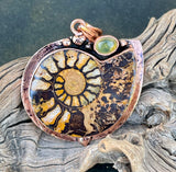 A beautiful blend of ancient history and warm, earthy elegance, this Ammonite pendant showcases the natural spiral fossil in a rich copper setting. The intricate patterns of the ammonite tell a story millions of years in the making, making this piece both eye-catching and meaningful.

Accented with a glowing amber stone, the pendant radiates warmth with its golden hues, perfectly complementing the copper tones.