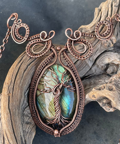 This enchanting necklace features a luminous Labradorite cabochon, cradled in an intricately handwoven copper frame with a Tree of Life design on the front. The flowing branches and detailed wirework highlight the stone’s mystical flashes of blue, green and yellow, symbolizing growth, grounding, and transformation. A meaningful and beautifully crafted piece, perfect for those who find magic in nature and strength in symbolism.
