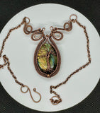 This enchanting necklace features a luminous Labradorite cabochon, cradled in an intricately handwoven copper frame with a Tree of Life design on the front. The flowing branches and detailed wirework highlight the stone’s mystical flashes of blue, green and yellow, symbolizing growth, grounding, and transformation. A meaningful and beautifully crafted piece, perfect for those who find magic in nature and strength in symbolism.