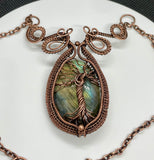 This enchanting necklace features a luminous Labradorite cabochon, cradled in an intricately handwoven copper frame with a Tree of Life design on the front. The flowing branches and detailed wirework highlight the stone’s mystical flashes of blue, green and yellow, symbolizing growth, grounding, and transformation. A meaningful and beautifully crafted piece, perfect for those who find magic in nature and strength in symbolism.