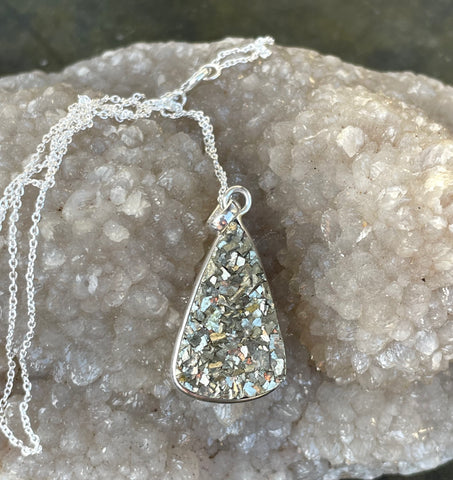 This Sterling Silver Pyrite Necklace features a captivating pyrite gemstone set in high-quality sterling silver, creating a striking and elegant piece of jewelry. Known for its metallic luster and shimmering appearance, pyrite adds a touch of sophistication and glamour to this classic necklace design.