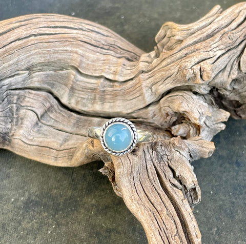 This Sterling Silver Blue Chalcedony Ring is an elegant piece of jewelry that highlights the calming beauty of blue chalcedony, set in a sleek sterling silver band. This ring combines the soothing, tranquil color of the gemstone with the timeless appeal of sterling silver, making it a versatile and stylish accessory.