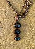 This Black Star Diopside Necklace in Copper is a captivating piece that showcases the mysterious beauty of three black star diopside gemstones, set in copper. The natural chatoyancy of the black star diopside, combined with the warm, earthy tones of copper, creates a stunning and unique accessory that is both elegant and striking.