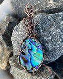 This Abalone Doublet Pendant features a stunning abalone shell layered in a doublet style, framed in handwoven copper. The vibrant, iridescent hues of the abalone shell—ranging from deep blues to greens and purples—contrast beautifully with the warmth of the copper. The doublet construction enhances the natural colors of the abalone, making this pendant an eye-catching piece that brings the beauty of the ocean to life.