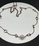 This Copper and Delicate Handmade White and Brown Striped Glass Bead Necklace is a beautifully handcrafted accessory, perfect for those who appreciate the fine craftsmanship of artisan jewelry. With its distinctive blend of warm copper tones and carefully designed glass bead, this necklace offers a sophisticated, earthy charm that appeals to a wide range of styles.