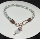 This handcrafted Kumihimo bracelet showcases a harmonious blend of blue and white hemp fibers, skillfully woven into a soft and intricate braid. The copper ends provide a warm contrast to the cool tones of the hemp, while an opalite bead dangle adds a touch of ethereal glow with its iridescent shimmer. Adjustable for a perfect fit, this bracelet is a beautiful fusion of natural textures and subtle elegance, perfect for boho and casual styles.