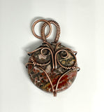 This unique pendant features a beautifully patterned Leopard Skin Jasper stone, nestled within a hand-sculpted copper owl design. The earthy tones and intricate patterns of the Jasper mirror the natural beauty of the wise owl, symbolizing wisdom and intuition. The copper detailing enhances the organic feel of the piece, making it a charming and meaningful accessory for nature lovers or those drawn to mystical symbolism.