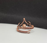 This enchanting ring features a luminous Peach Moonstone, wrapped in handwoven copper wire that enhances the stone's warm, soft glow. The adjustable design ensures a comfortable fit, while the earthy copper beautifully complements the Moonstone’s natural shimmer. Perfect for those who love mystical stones and handcrafted jewelry, this ring adds a touch of elegance and warmth to any ensemble.