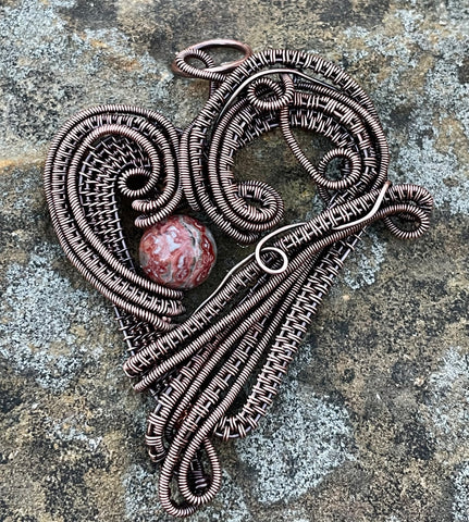 This Heart Pendant features layers of handwoven copper weaves and coils and a Leopard Skin Jasper Bead Accent. 