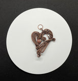 This Heart Pendant features layers of handwoven copper weaves and coils and a Leopard Skin Jasper Bead Accent. 