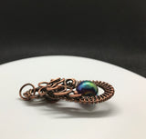 This Woven Copper and Copper Swirls Accent Rainbow Colored Glass Bead Pendant is an eye-catching piece of jewelry that combines a&nbsp;vibrant rainbow-colored glass bead with the warm and earthy tones of woven copper. The intricate copper swirls and handcrafted wirework enhance the pendant’s charm, creating a beautiful fusion of bold colors and artisan craftsmanship.