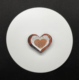 This heart pin is made of red patinated Copper, embossed Aluminum and a hammered Copper Heart on top.