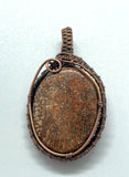 Red Fossilized Dinosaur Bone Cabochon Pendant wrapped in handwoven copper.