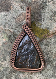 This extraordinary pendant features an authentic piece of the Canyon Diablo Meteorite, skillfully wrapped in warm, earthy copper wire. The meteorite's rugged texture and metallic sheen are beautifully complemented by the copper’s natural hue, creating a striking contrast that highlights its cosmic origins. A perfect piece for those who love unique, space-inspired jewelry, this pendant is a true conversation starter with a piece of the stars.