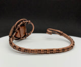 Heavy gauge Copper forms the base of this bracelet with a shimmering Goldstone Cabochon caught in the copper weaves. 