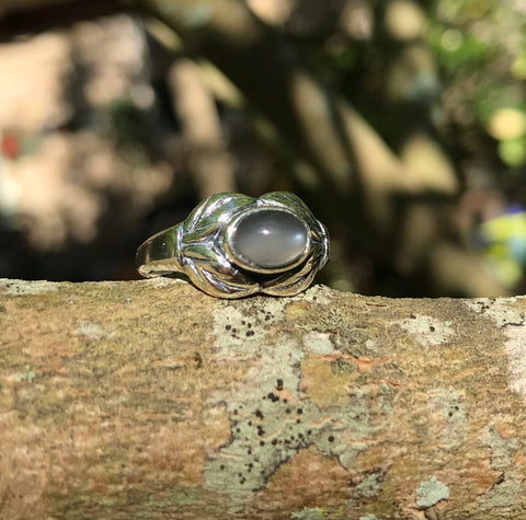 This sterling silver ring features a luminous gray moonstone, glowing with soft flashes of light. Set in polished sterling silver, the design highlights the stone’s natural beauty while offering a classic, elegant look. Sized at 7, this ring is perfect as a versatile everyday piece or a subtle statement for special occasions.