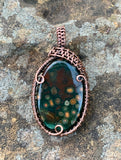 Colorful orbs sprout out in this dark green and red Jasper Pendant in Copper. 