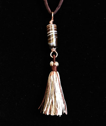 Elevate your style with the Brown Striped Column Agate Necklace, a beautifully designed piece that combines the natural elegance of striped agate with the luxurious feel of silk. This necklace features a stunning column of brown striped agate, complemented by a matching tassel, and is suspended on an adjustable silk cord, offering both versatility and sophistication.