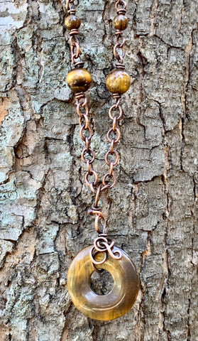 This necklace features a freeform wrapped Tiger Eye Bead on a copper chain with Tiger Eye Bead Accents.