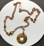 This necklace features a freeform wrapped Tiger Eye Bead on a copper chain with Tiger Eye Bead Accents.