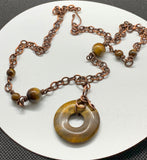 This necklace features a freeform wrapped Tiger Eye Bead on a copper chain with Tiger Eye Bead Accents.