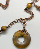 This necklace features a freeform wrapped Tiger Eye Bead on a copper chain with Tiger Eye Bead Accents.