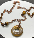 This necklace features a freeform wrapped Tiger Eye Bead on a copper chain with Tiger Eye Bead Accents.