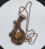 Bold size pendant features hand wrapped copper curves and swirls around a colorful agate.